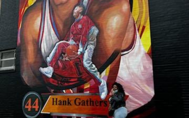 Brtini Campbell posing with Hank Gathers mural