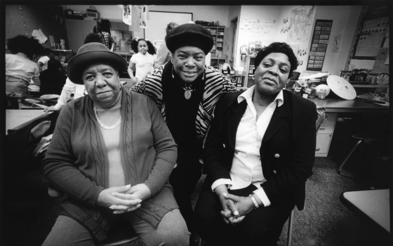 Three woman sitting in a row smiling at the camera