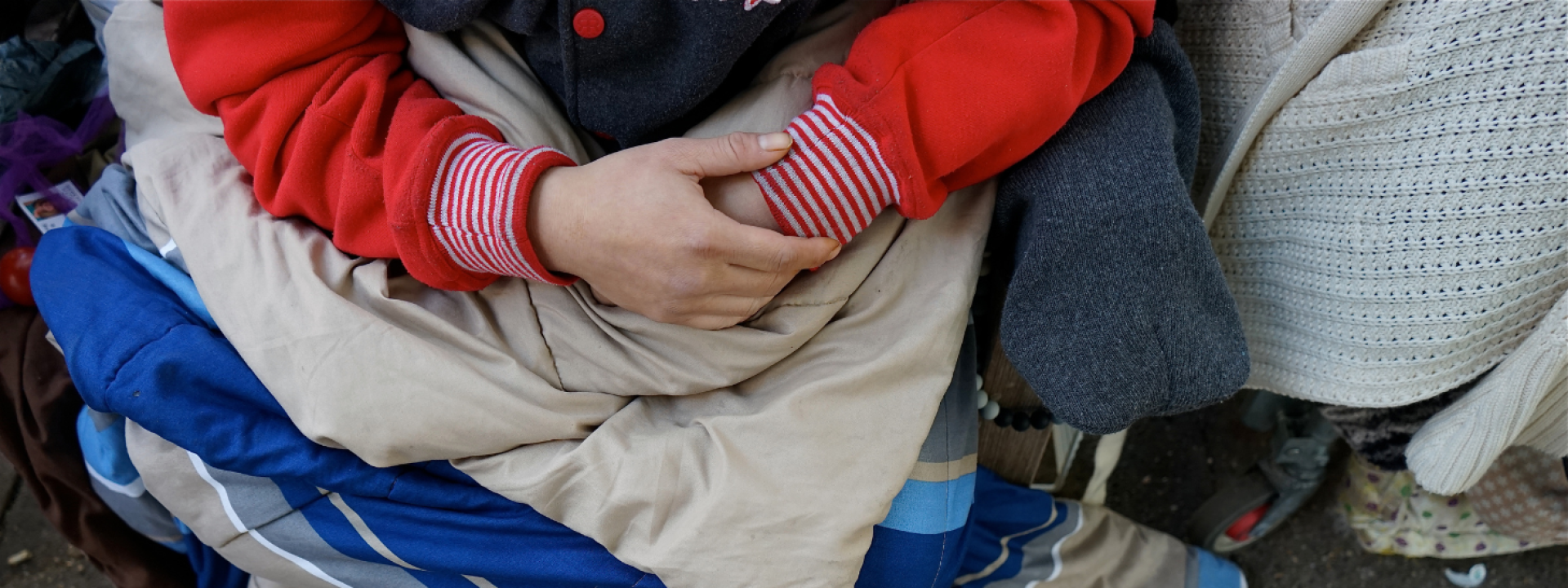 man sitting on ground, only his hands showing
