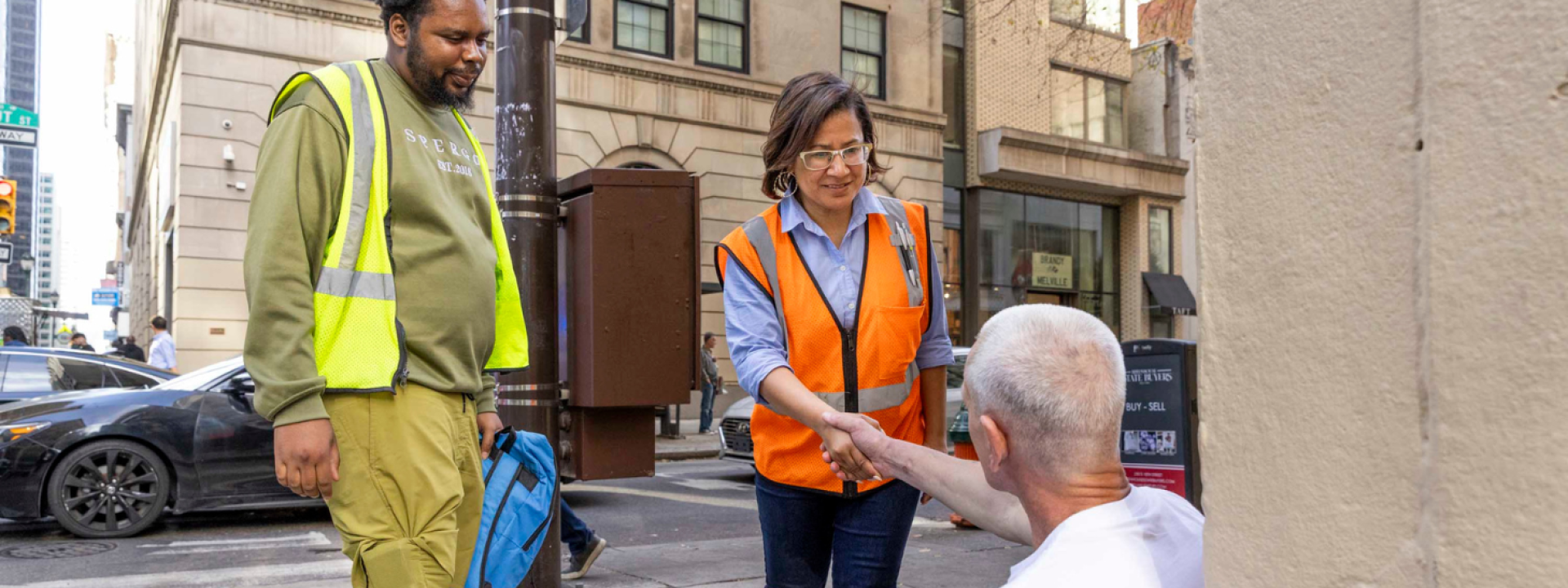 Donna Bullock shaking hands with a man sitting on the sidewalk