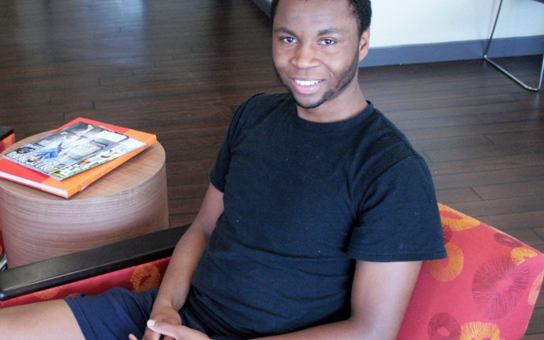 Young person sitting in chair with hands folded