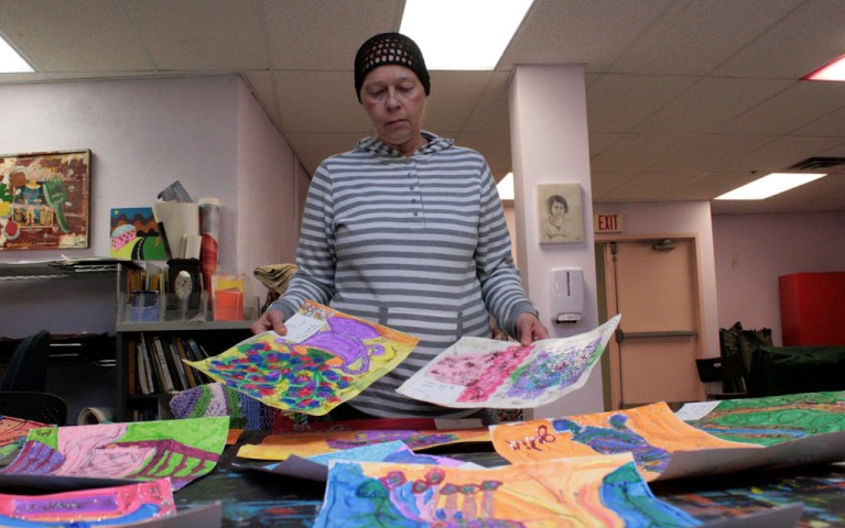 Project HOME resident Julia reviewing a collection of her paintings