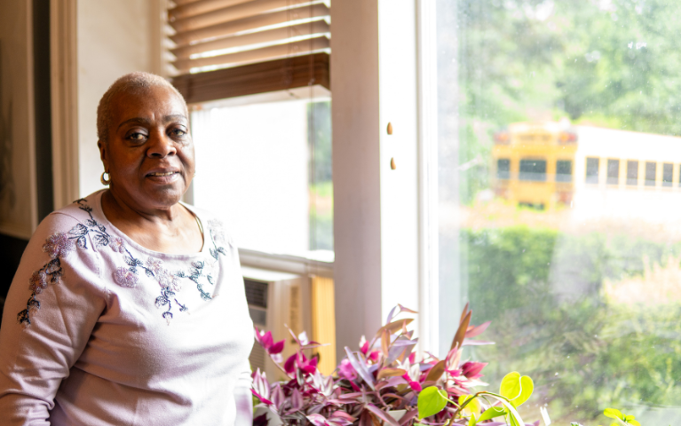 A woman standing by a sunny window.