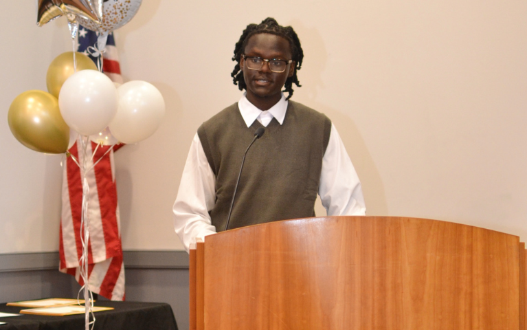 A young man standing at a podium delivering a speech