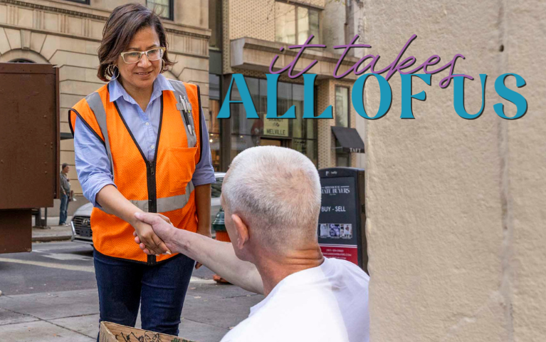 Donna Bullock shaking hands with a man sitting on the sidewalk
