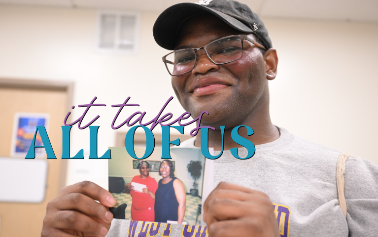 A smiling man holds up a picture showing two women