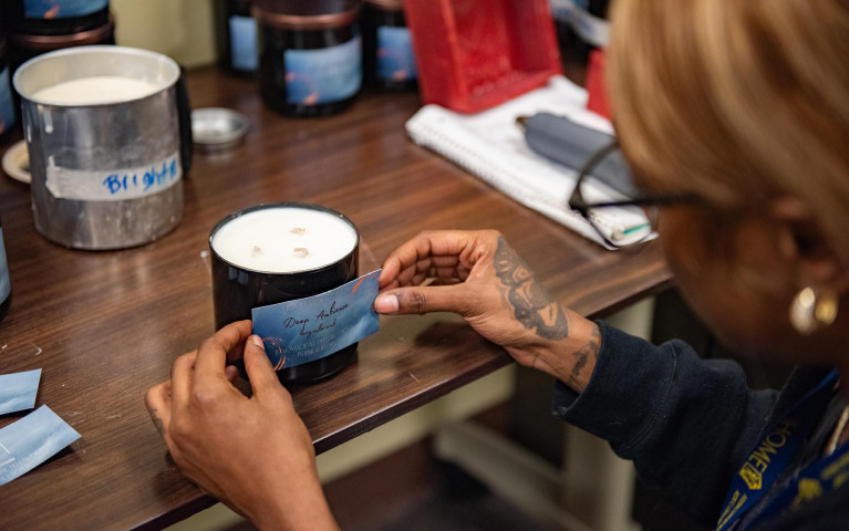 A woman applying a label to a candle