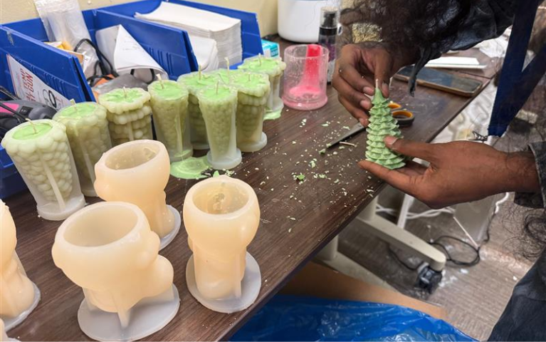 Tynijah working with a candle in their workshop.