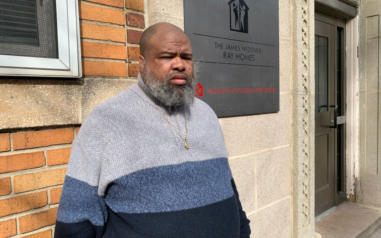 Project HOME resident Jason poses in front of the James Widener Ray  Homes building where he lives.