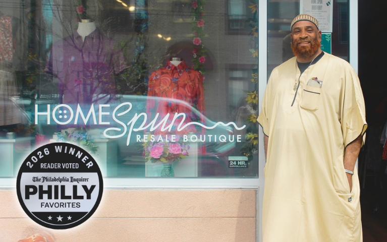 HOMEspun Boutique manager stands outside the store. Mannequins wearing colorful button-downs are visible through the window. A Silver badge in the lower left reads 2026 Winner, Reader Voted, The Philadelphia Inquirer, Philly Favorites.