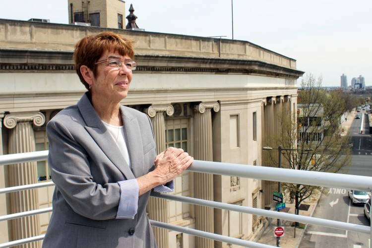 Project HOME Co-Founder Sister Mary Scullion rests her hands on a railing on top of our JBJ Soul Homes building with the view of the city of Philadelphia behind her. 