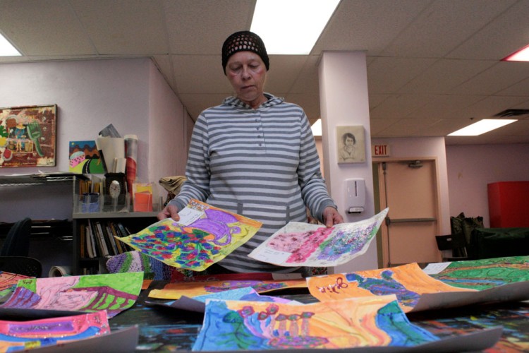 Project HOME resident Julia reviewing a collection of her paintings