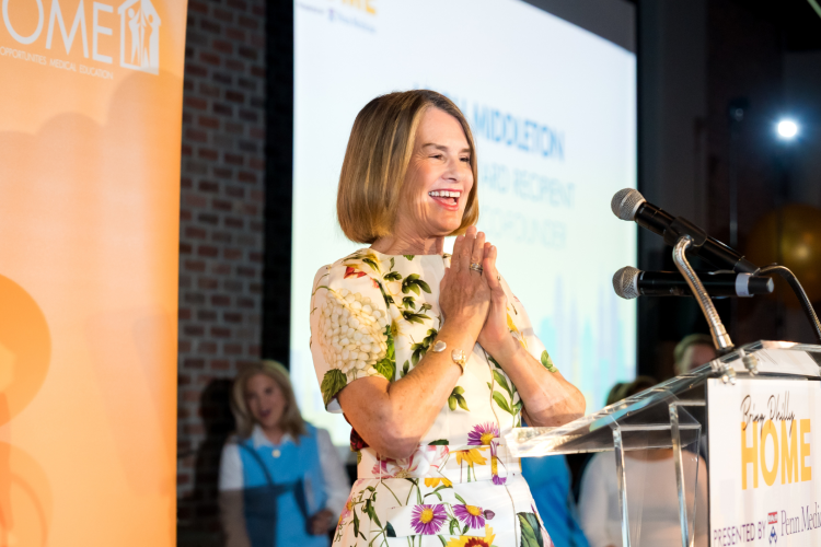 Leigh Middleton standing at a podium smiling.