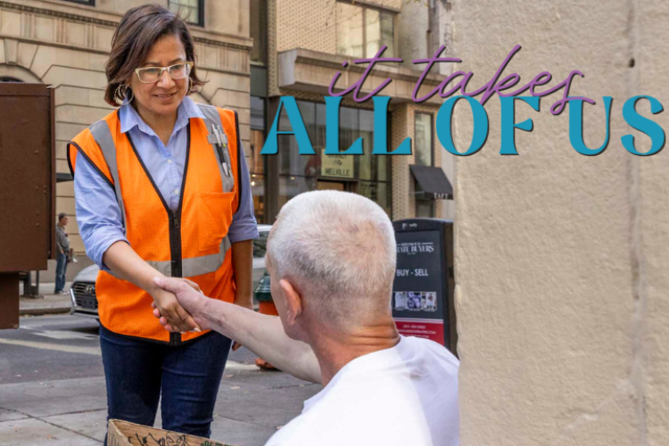 Donna Bullock shaking hands with a man sitting on the sidewalk