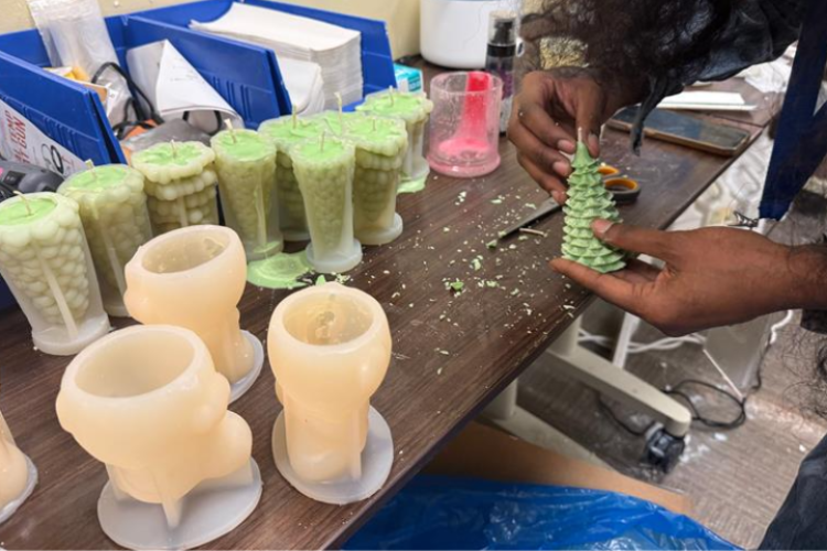 Tynijah working with a candle in their workshop.