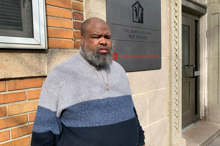 Project HOME resident Jason poses in front of the James Widener Ray  Homes building where he lives.