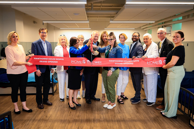 A line of people holding a red ribbon, with two of them cutting in with giant scissors.